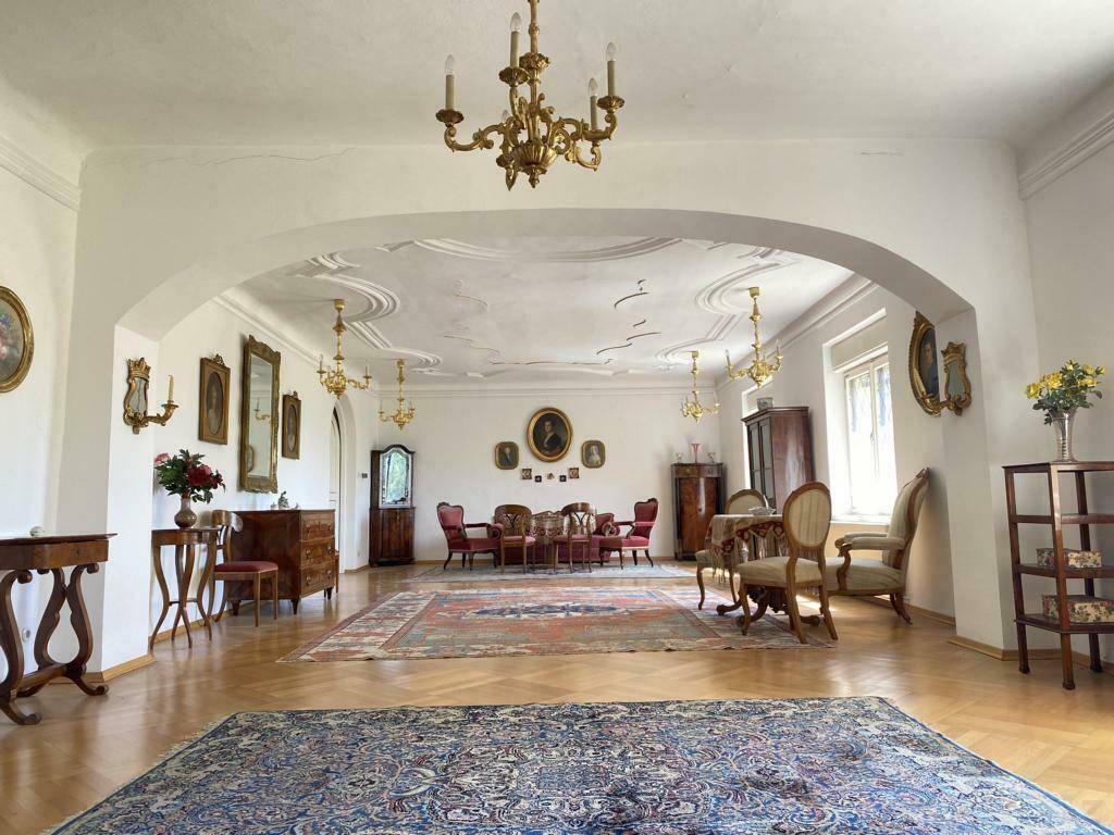 Großzügiger, lichtdurchfluteter Salon mit Parkettboden, Kronleuchtern und antiken Möbeln.