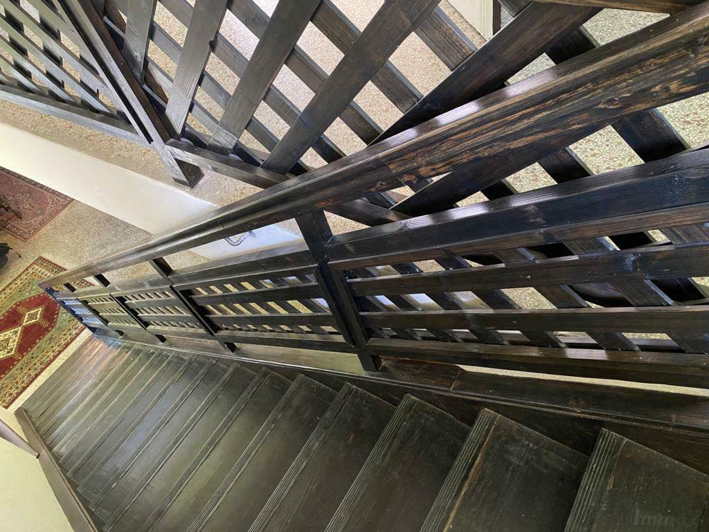 Dunkle Holztreppe mit kunstvollem Geländer, die zu den oberen Etagen führt.
