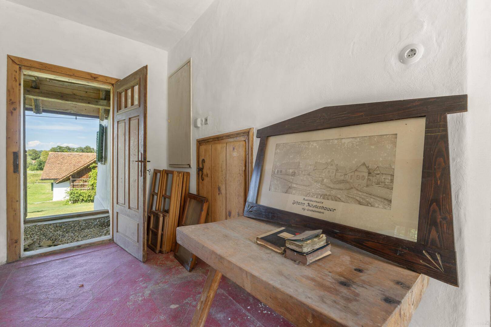 Eingangsbereich mit offener Holztür, die den Blick auf die ländliche Umgebung freigibt.