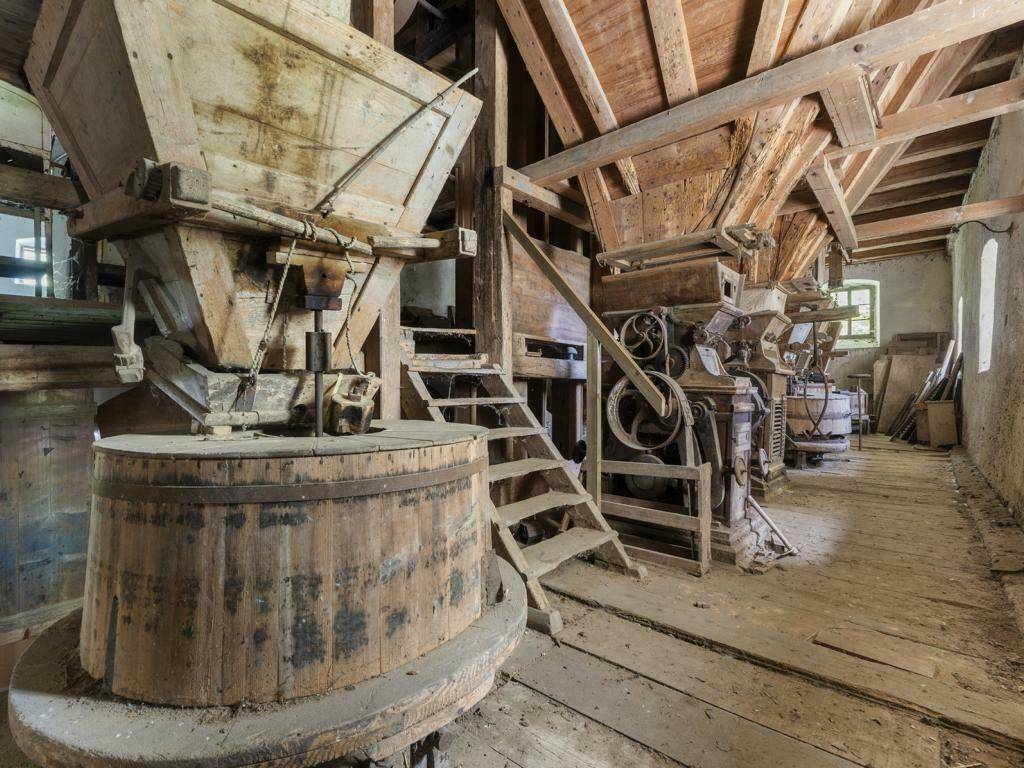 Historische Mühlenmaschinen aus Holz und Metall in einem alten, rustikalen Gebäude.