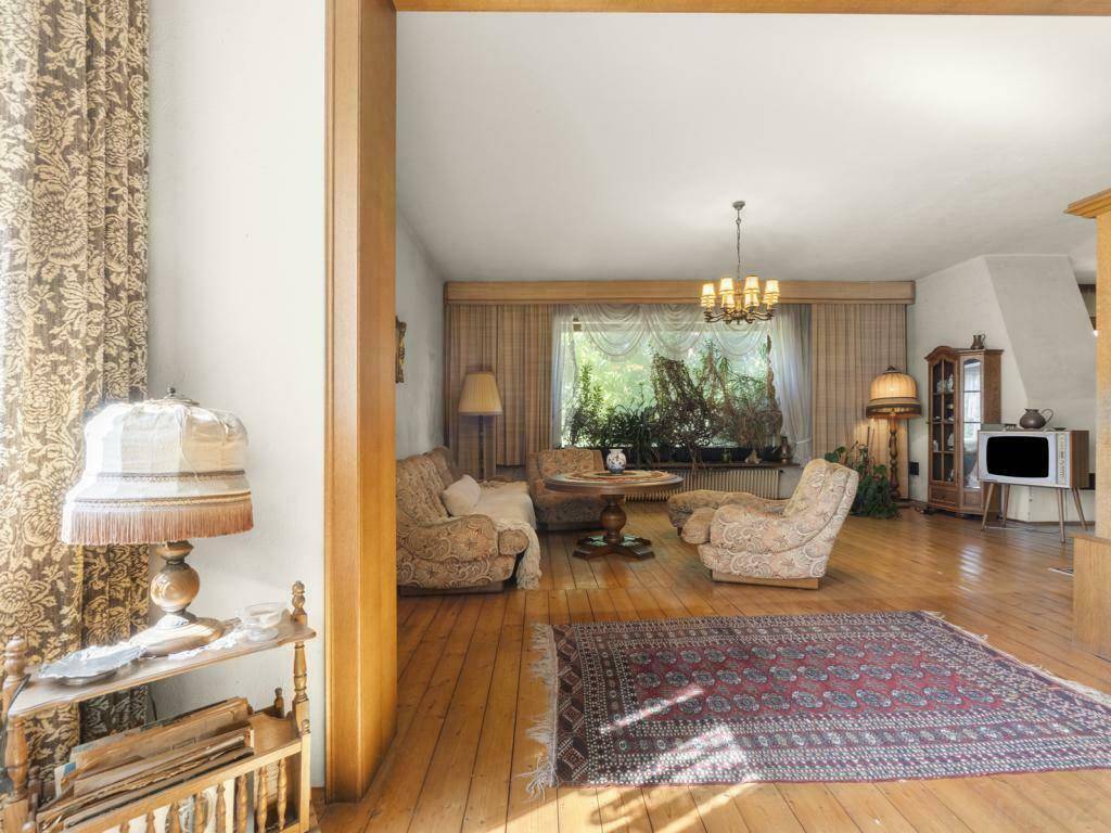Gemütliches Wohnzimmer mit Holzdielenboden, traditionellen Möbeln und großen Fenstern.