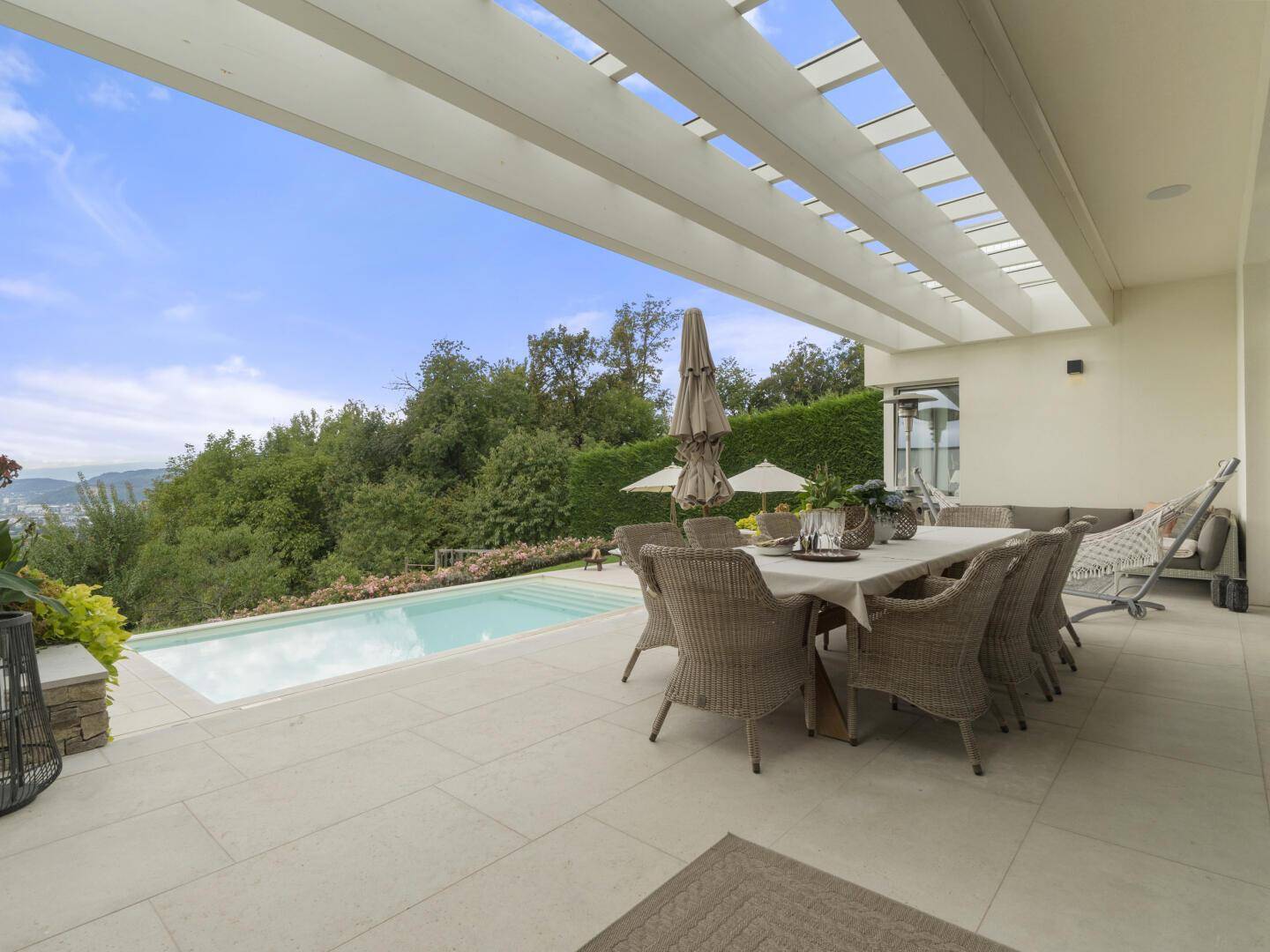 Überdachte Terrasse mit Esstisch, Lounge-Bereich und direktem Zugang zum Pool.