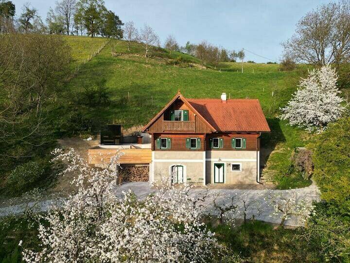 Charmantes Landhaus mit traditioneller Architektur und blühenden Bäumen im Frühling.