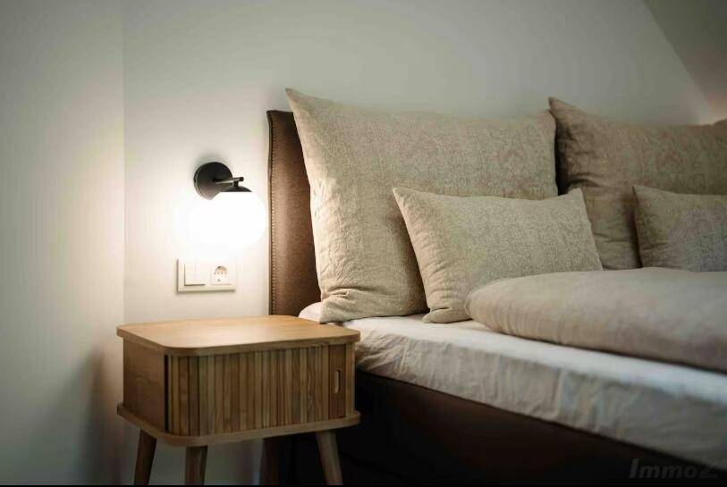 Detailansicht des Bettes mit bequemen Kissen und Nachttisch im Schlafzimmer.