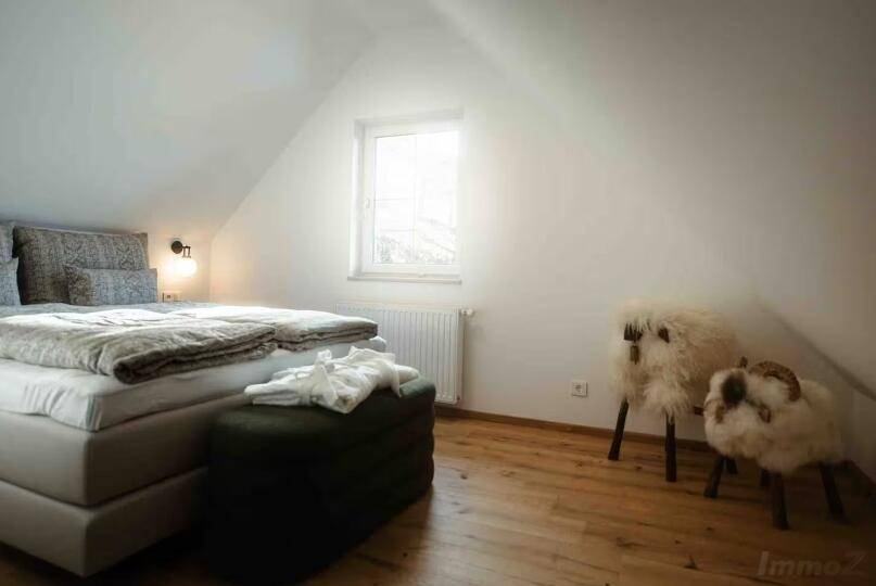 Helles Schlafzimmer im Dachgeschoss mit Holzboden und schrägen Wänden.