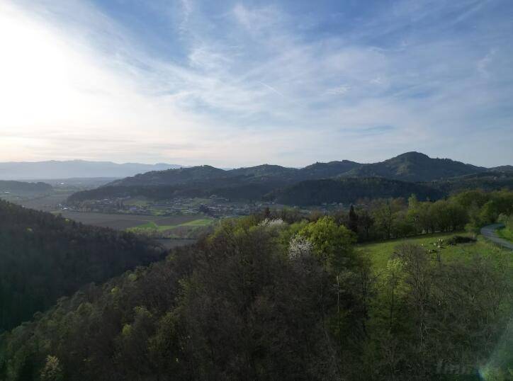 Weitläufiger Panoramablick über grüne Hügel, Wälder und ein Tal mit Siedlungen.
