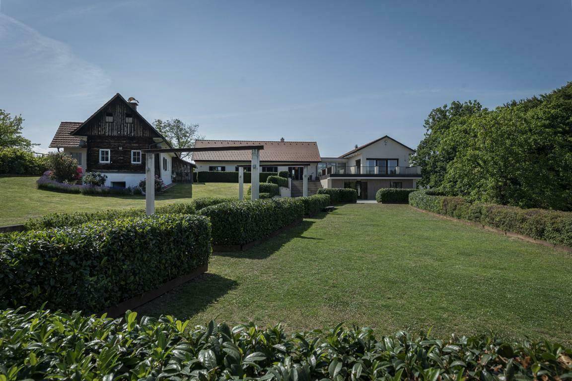 Weitläufiger Garten mit Rasenflächen und Hecken, umgeben von mehreren Gebäuden des Anwesens.