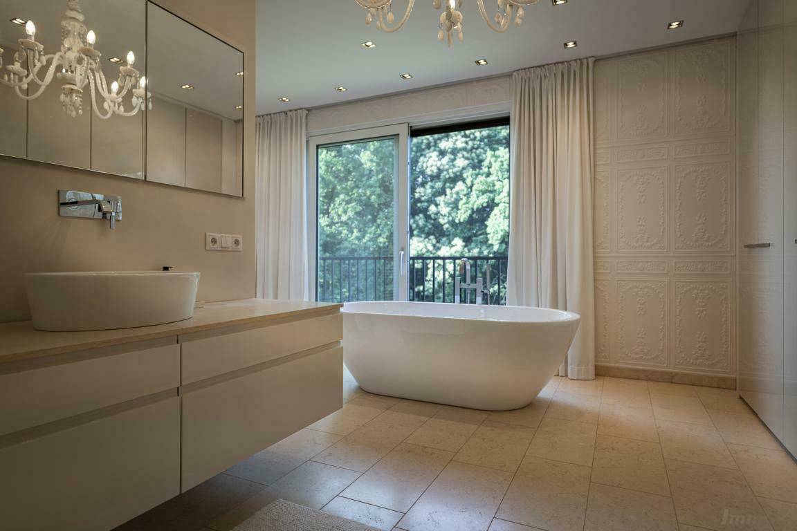 Luxuriöses Badezimmer mit freistehender Badewanne, Doppelwaschbecken und Zugang zum Balkon.