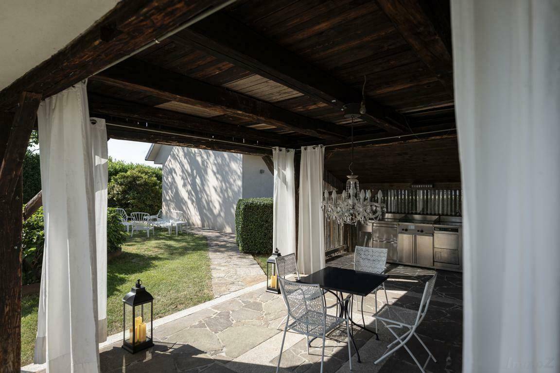 Überdachte Terrasse mit Außenküche, Essbereich und Kronleuchter für gesellige Stunden.