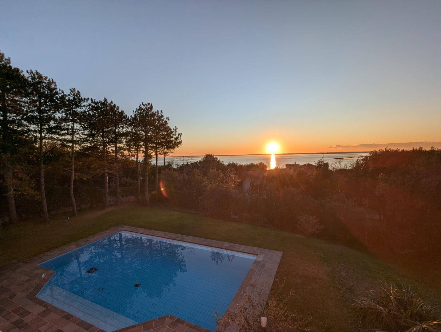 Malerischer Sonnenuntergang über dem Wasser, genossen vom privaten Poolbereich.