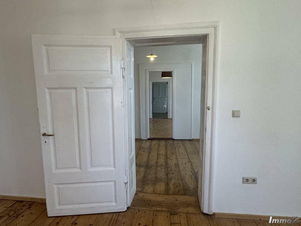 Langer Flur mit Holzdielenboden und mehreren Türen, die in verschiedene Räume führen.