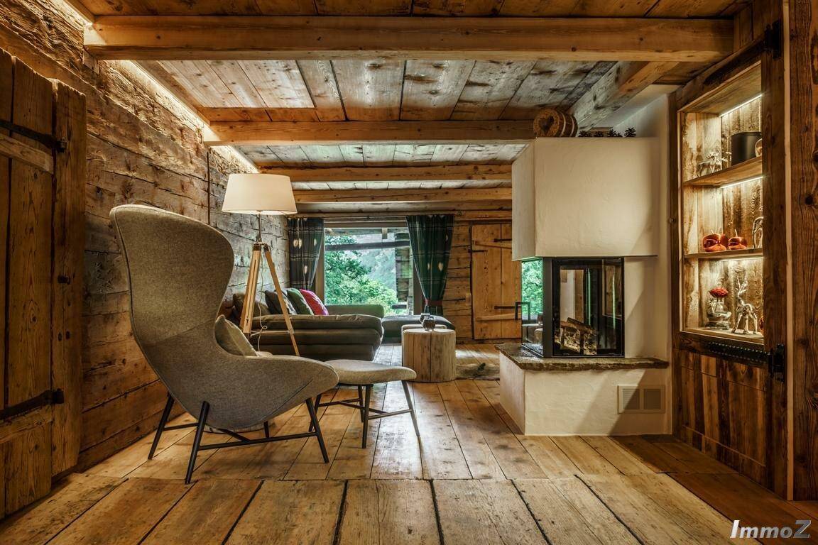 Stilvolles Wohnzimmer mit Kamin, Holzbalken und modernem Sessel in alpiner Atmosphäre.