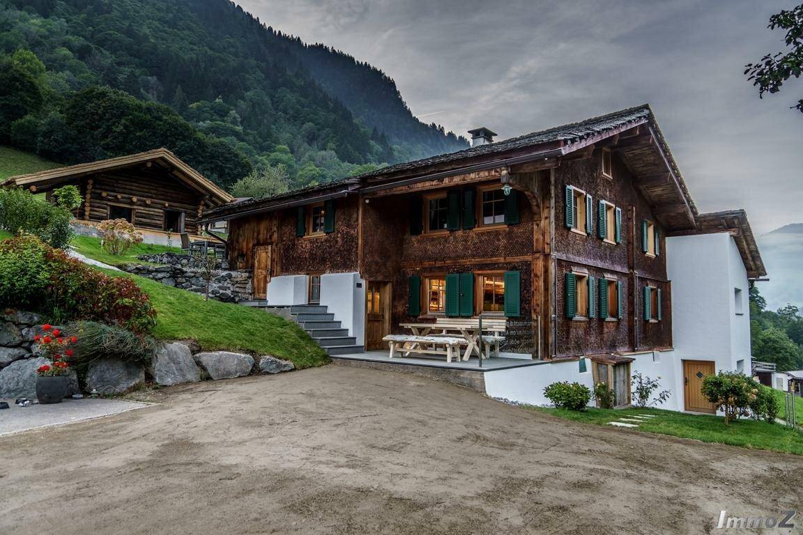 Großes Holzhaus mit traditioneller Architektur, Auffahrt und Bergblick.