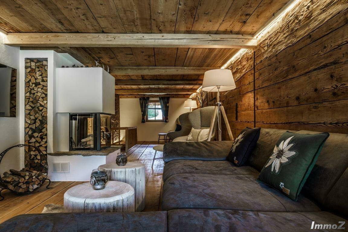 Gemütliches Wohnzimmer mit Kamin, Holzwänden und -decke, sowie einem großen Sofa.
