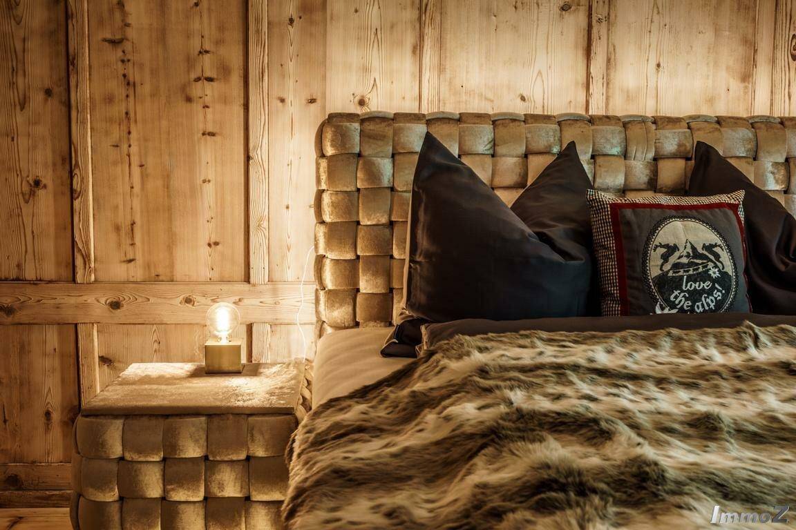Gemütliches Schlafzimmer mit Holzwänden, strukturiertem Kopfteil und weicher Bettdecke.