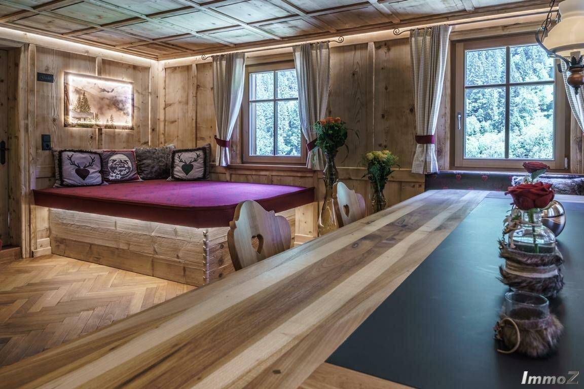 Traditioneller Essbereich mit eingebauter Sitzbank, Holzwänden und -decke sowie Blick ins Grüne.