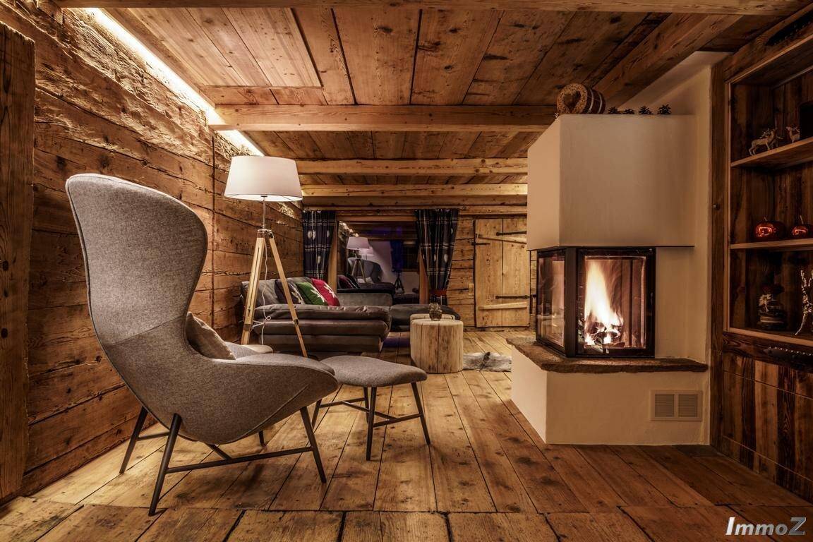 Stilvolles Wohnzimmer mit Kamin, Holzbalken und modernem Sessel in alpiner Atmosphäre.