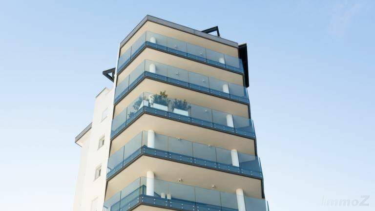 Moderne Architektur des Gebäudes mit mehreren Balkonen und eleganten Glasgeländern.
