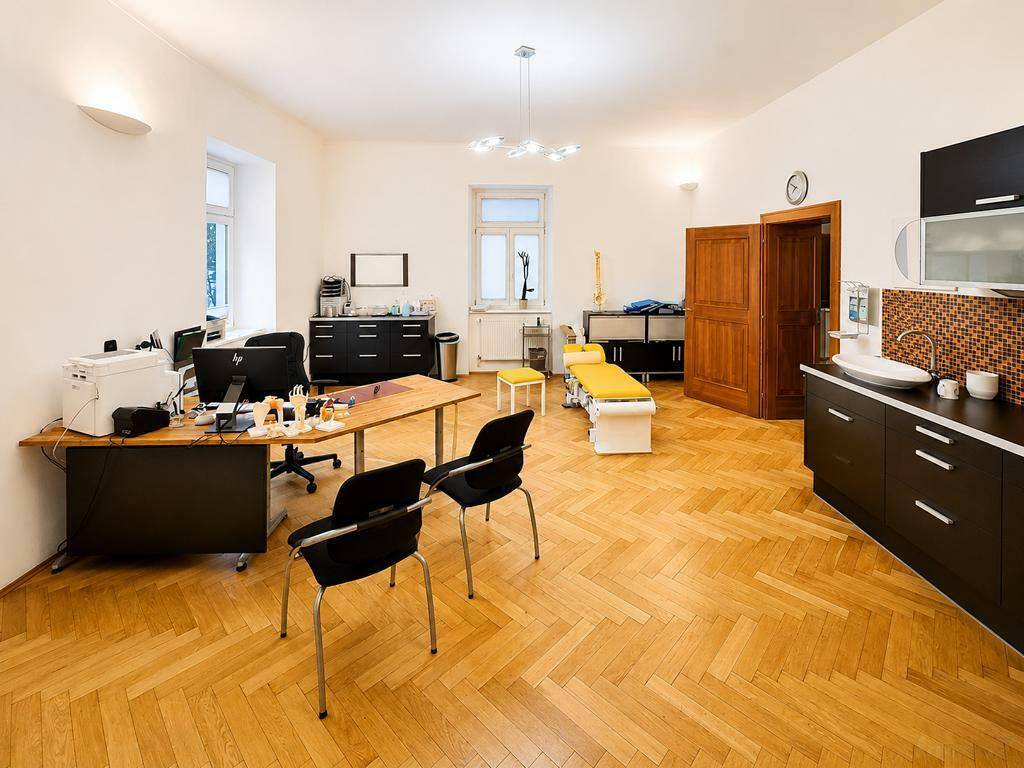 Geräumiges Büro oder Praxisraum mit Holzboden, Schreibtischen und integrierter Küchenzeile.