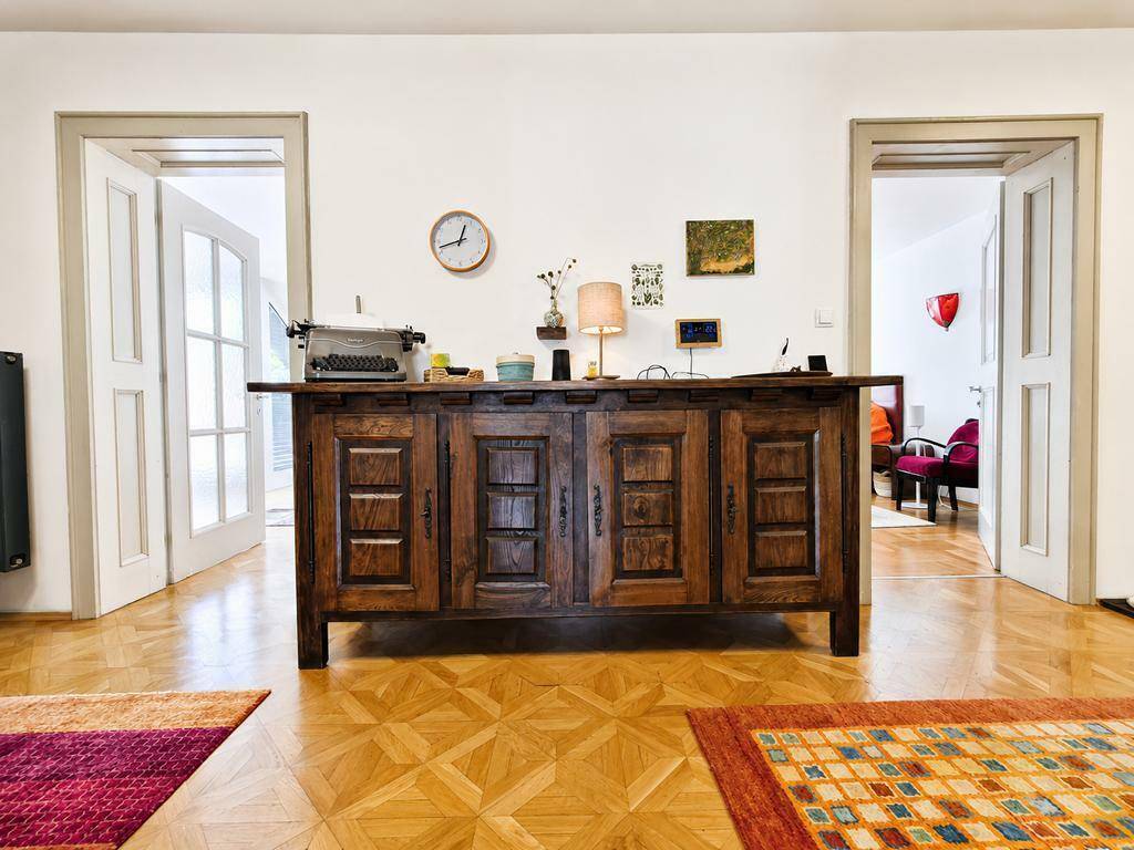 Heller Innenraum mit Holzboden und einem antiken Holzschrank zwischen zwei Türen.