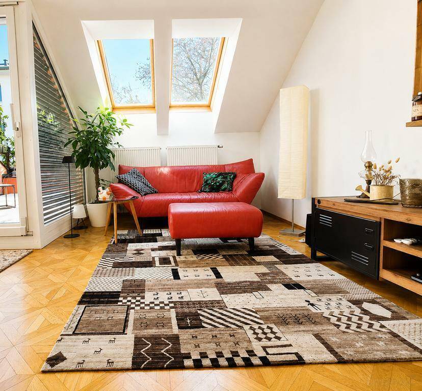 Gemütliches Wohnzimmer mit rotem Sofa, Holzboden und Dachfenstern für viel Tageslicht.