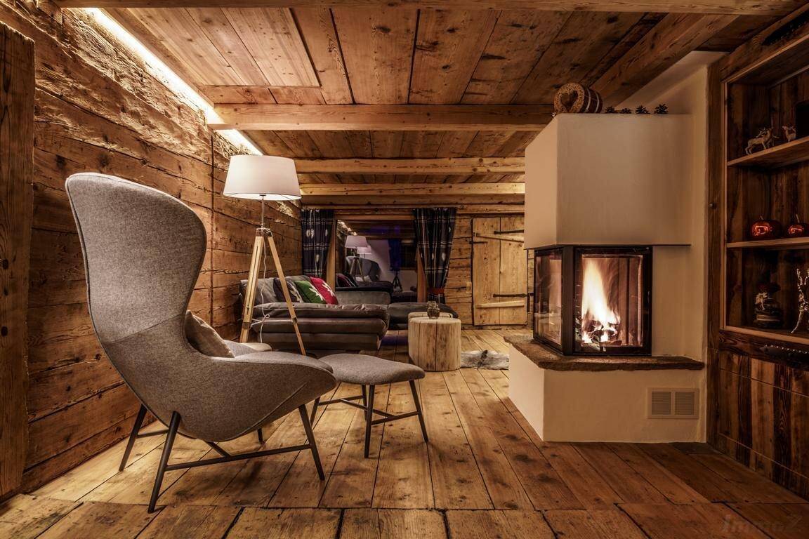 Rustikales Wohnzimmer mit Kamin, Holzboden und gemütlichem Sessel im Landhausstil.