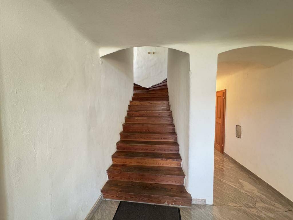 Holztreppe mit weißen Wänden und Marmorboden im Eingangsbereich, führt in die oberen Stockwerke.