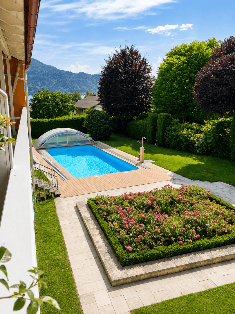 Gepflegter Gartenbereich mit Swimmingpool, Holzdeck und Blumenbeeten.