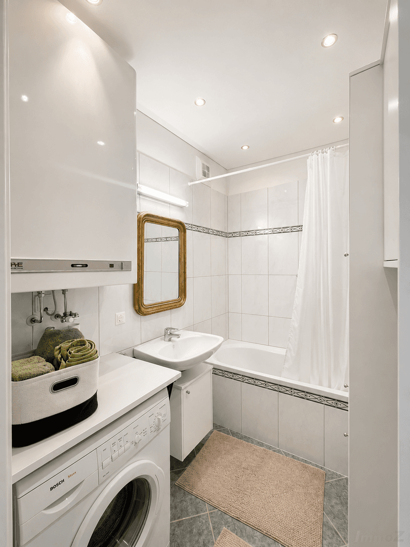 Badezimmer mit Badewanne, Waschbecken und integrierter Waschmaschine.