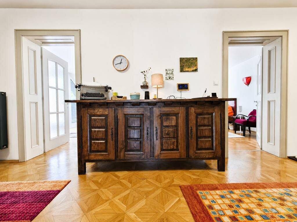 Heller Flur mit Holzboden und einem rustikalen Holzschrank zwischen zwei Flügeltüren.