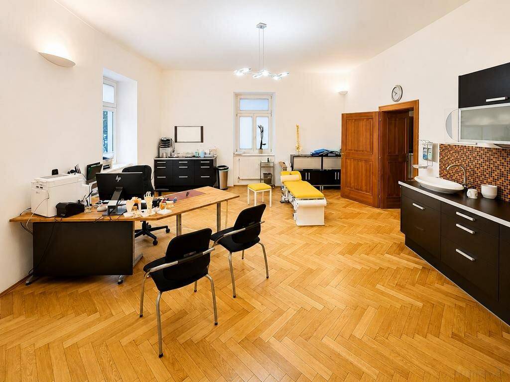 Geräumiges Büro oder Praxiszimmer mit Parkettboden, Schreibtischen und integrierter Küchenzeile.