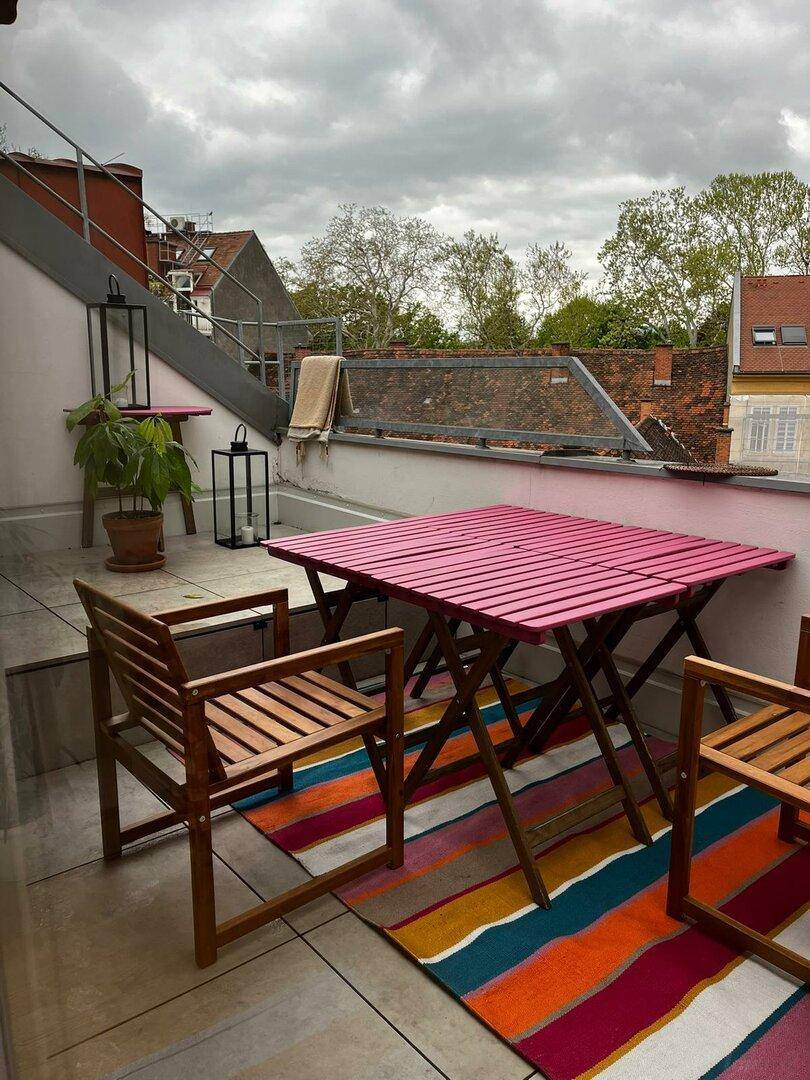 Geräumige Dachterrasse mit Sitzgelegenheiten und Blick auf die umliegenden Dächer, ideal für entspannte Stunden.