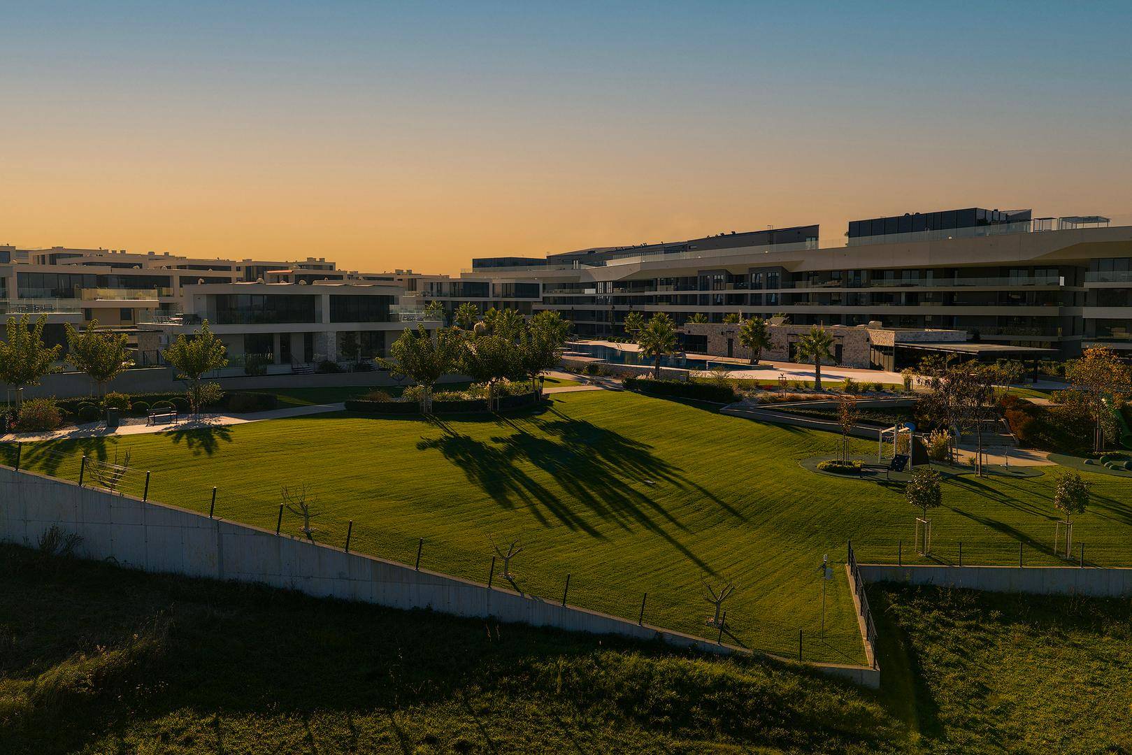 Weitläufige Grünflächen und moderne Wohngebäude in einer gepflegten Anlage mit Blick auf die Landschaft.