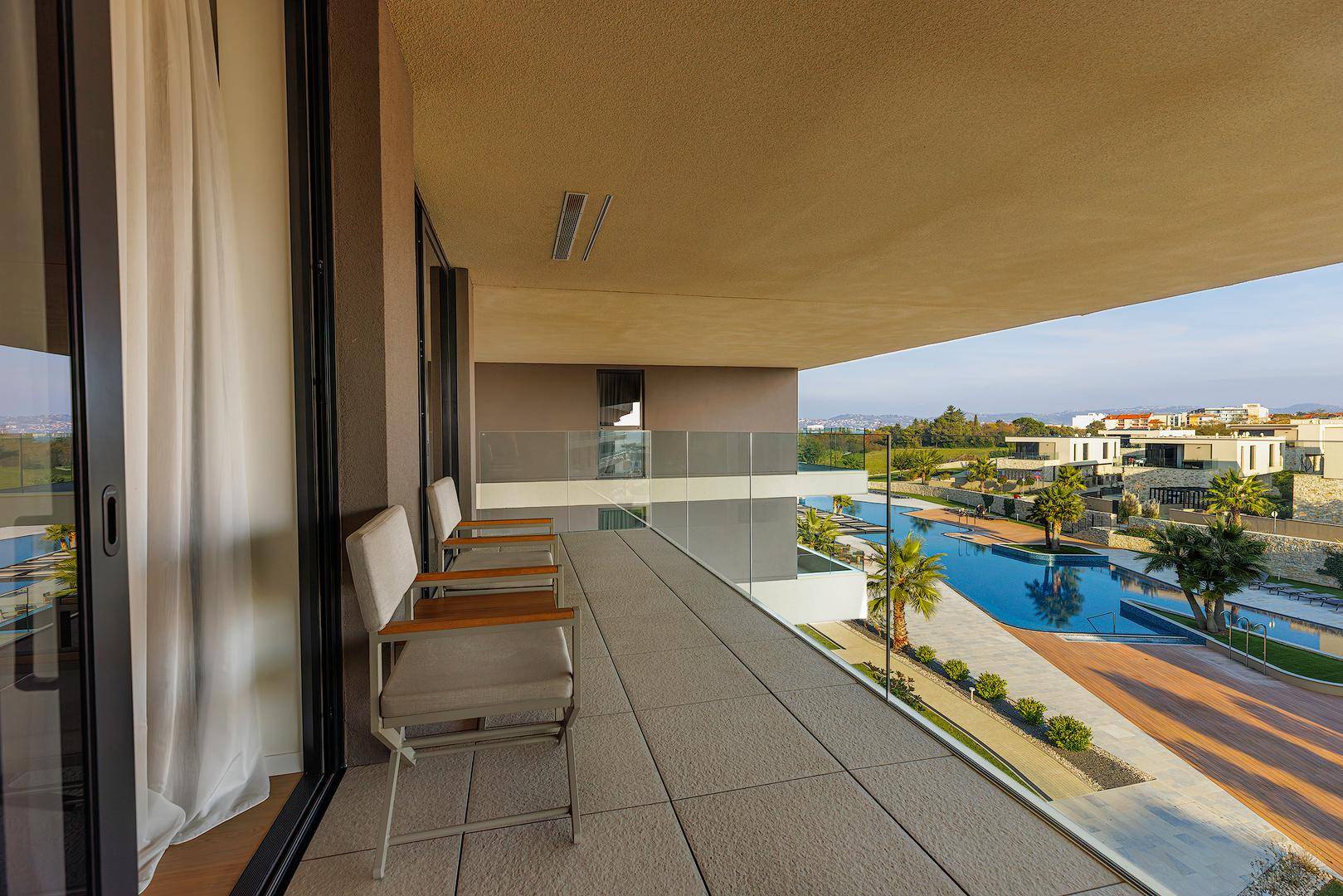 Geräumiger Balkon mit Sitzgelegenheiten und weitem Blick über die Poolanlage und die Umgebung.