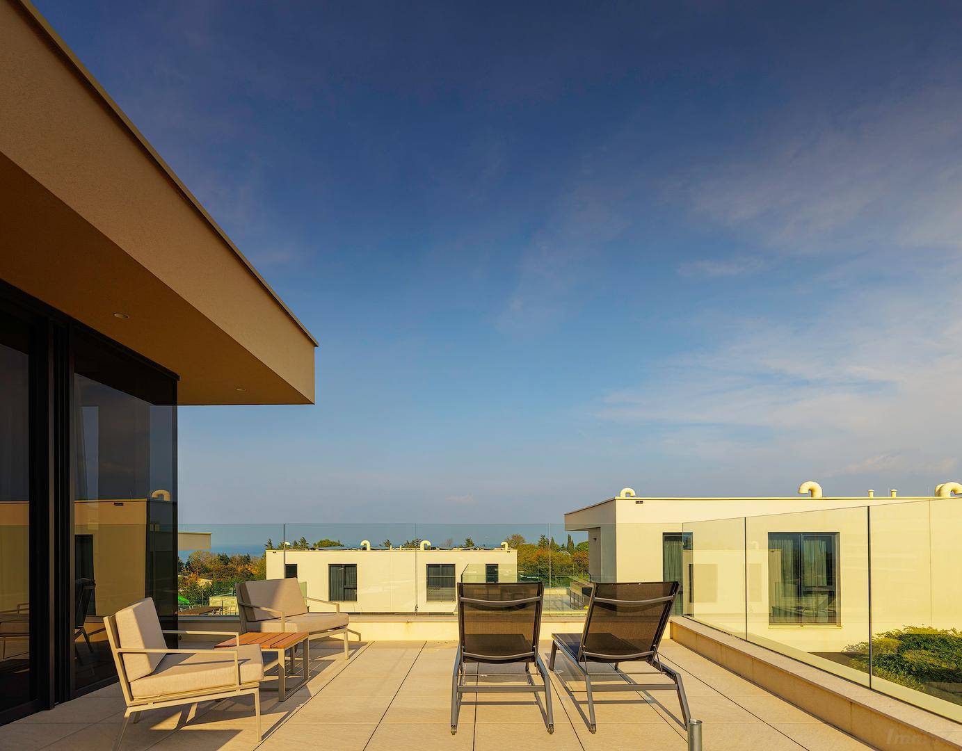 Geräumige Dachterrasse mit Sitzgelegenheiten und weitem Blick auf das Meer.