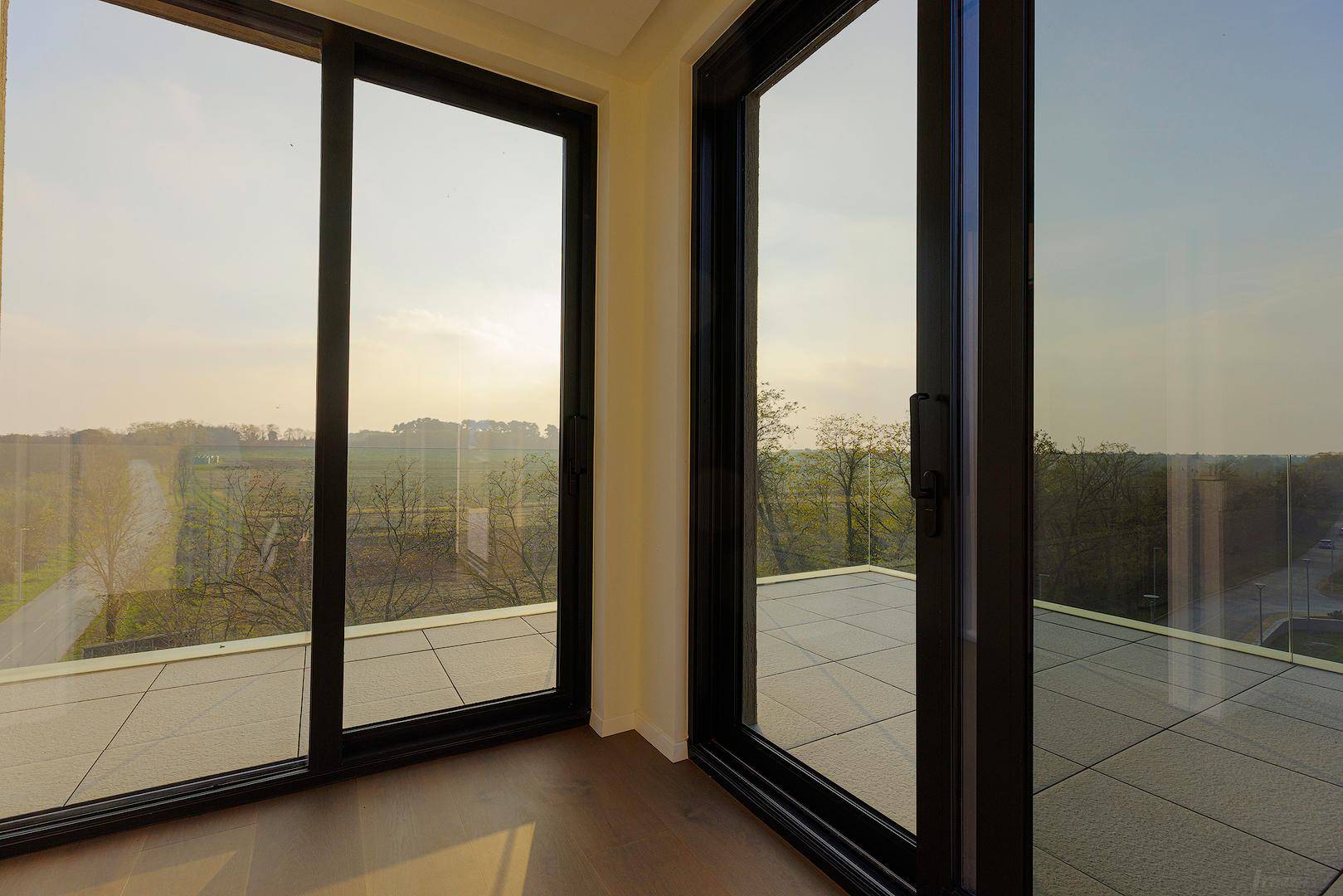 Heller Innenraum mit großen Schiebetüren, die Zugang zu einer Terrasse mit weitem Blick bieten.