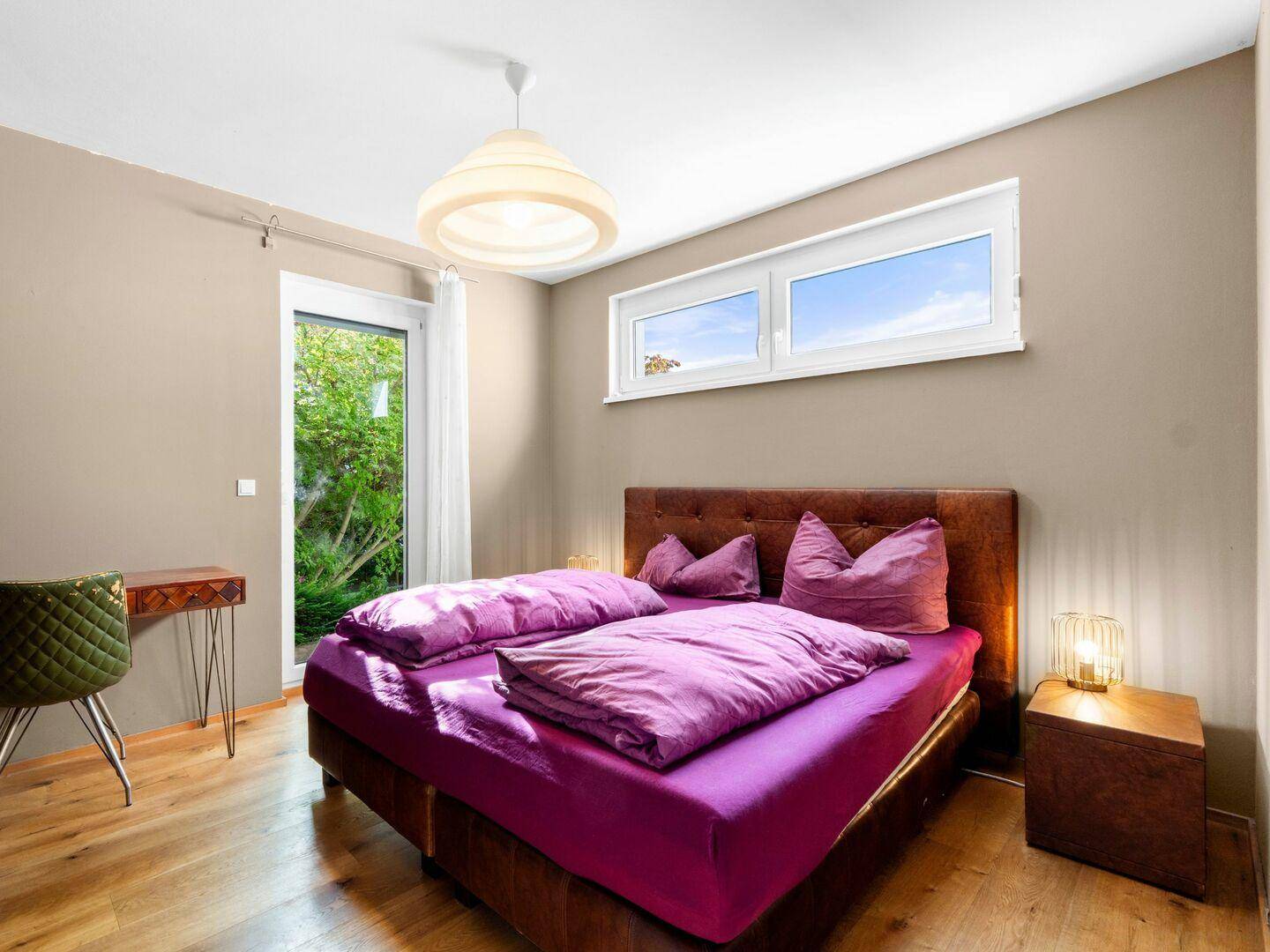Gemütliches Schlafzimmer mit Doppelbett, Nachttischen und Zugang zum Außenbereich.