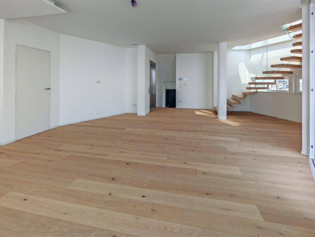 Geräumiger Wohnbereich mit Holzboden, eleganter Wendeltreppe und direktem Zugang zum Aufzug.