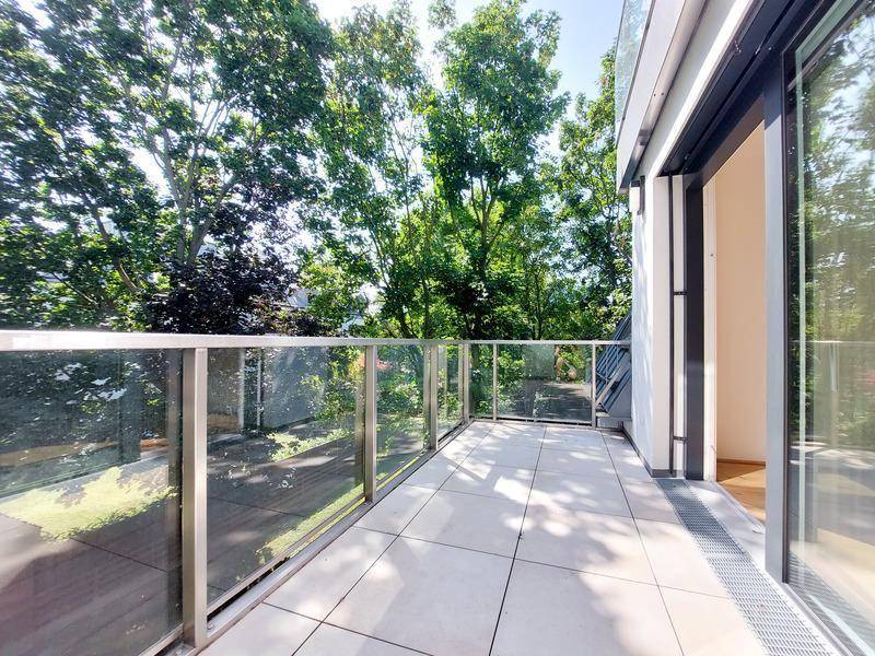 Geräumiger Balkon mit Glasgeländer und Blick ins Grüne, ideal zum Entspannen.