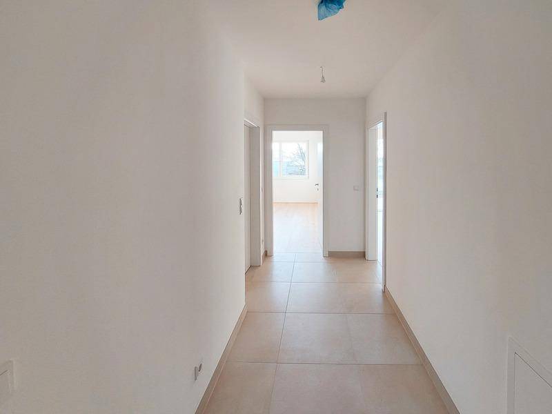 Heller Flur mit modernen Fliesen und Zugang zu weiteren Zimmern der Wohnung.
