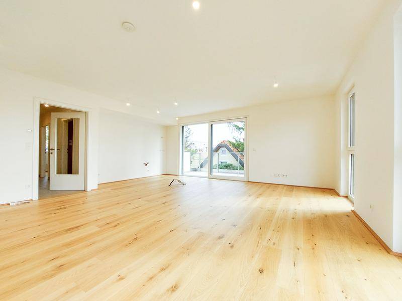 Helles, geräumiges Wohnzimmer mit Holzboden und großen Schiebetüren, die viel Tageslicht hereinlassen.