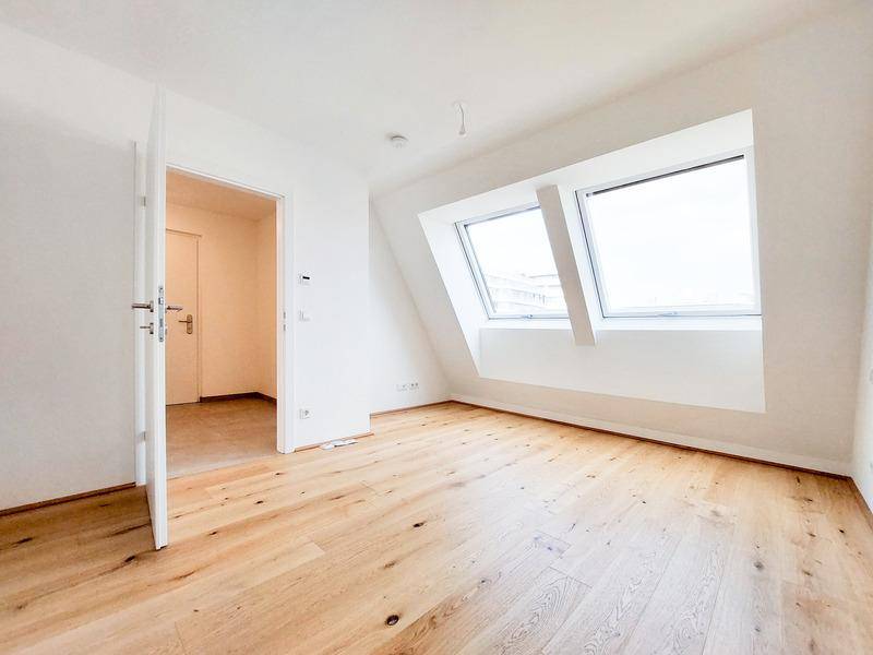 Gemütliches Zimmer im Dachgeschoss mit schrägen Wänden und zwei Dachfenstern für viel Helligkeit.