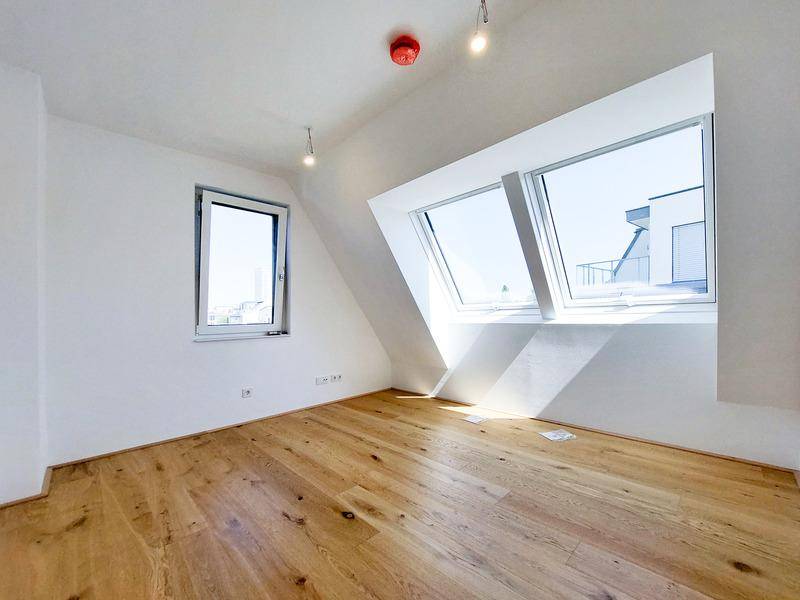 Helles Schlafzimmer im Dachgeschoss mit schrägen Wänden, großen Dachfenstern und neuem Parkettboden.
