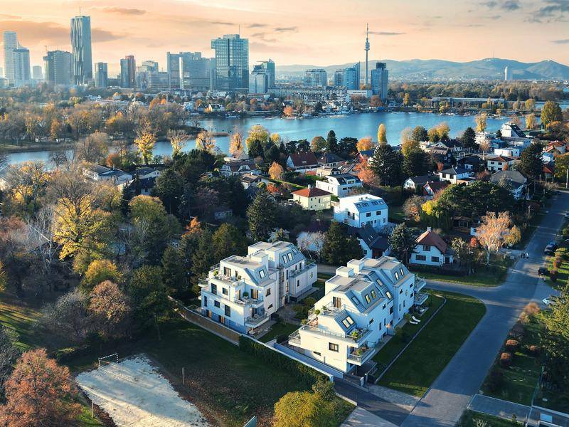 Luftaufnahme moderner Gebäude mit Blick auf die Stadt Wien, die Donau und umliegende Grünflächen.