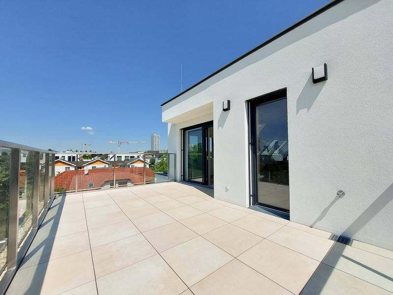 Große, sonnige Dachterrasse mit Fliesenboden und Glasgeländer, ideal für Entspannung im Freien.