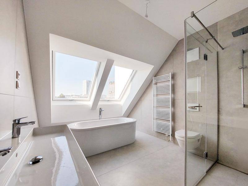 Modernes Badezimmer im Dachgeschoss mit freistehender Badewanne, Dusche und Dachfenstern.