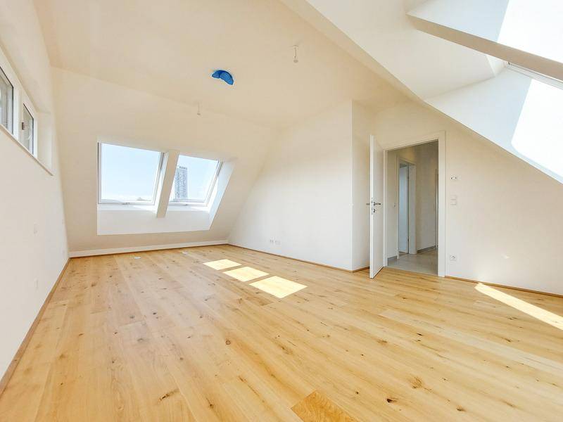 Geräumiges Dachgeschosszimmer mit Holzboden, Dachfenstern und Zugang zu weiteren Räumen.