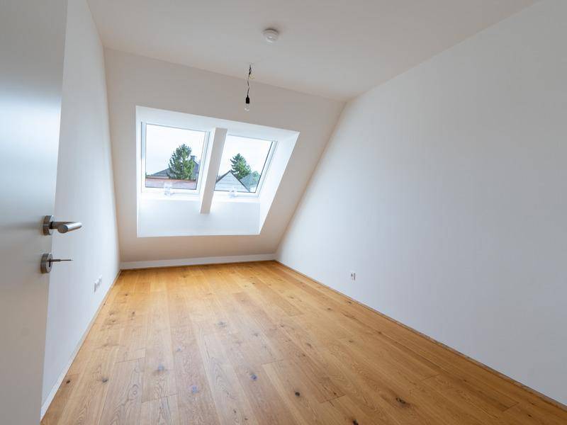 Gemütliches Schlafzimmer im Dachgeschoss mit Holzboden und zwei Dachfenstern.