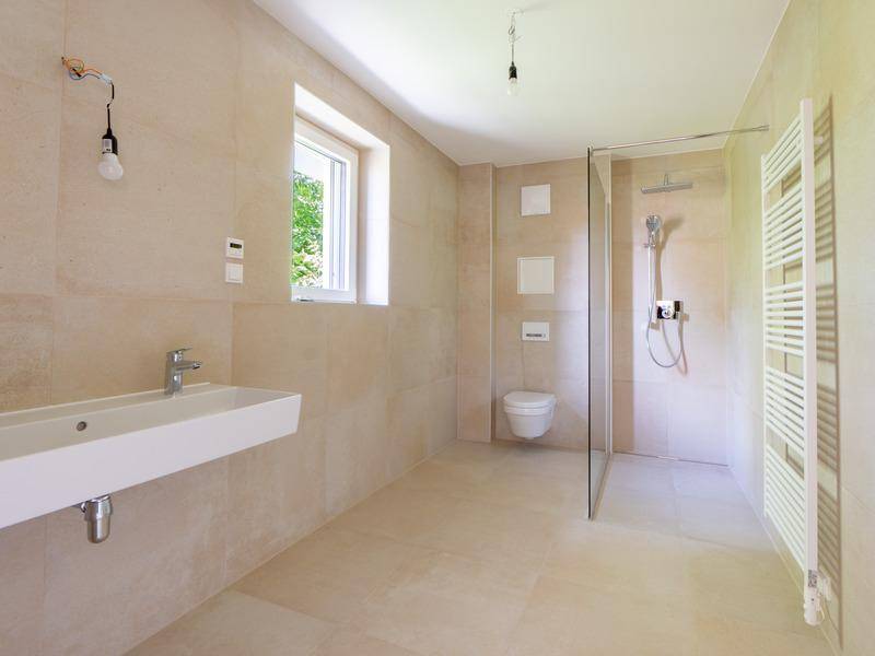 Modernes Badezimmer mit beigen Fliesen, Einzelwaschbecken, ebenerdiger Dusche und Fenster.