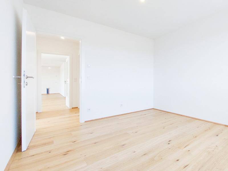 Heller Flur mit Holzboden, der zu weiteren Zimmern der Wohnung führt und viel Tageslicht bietet.